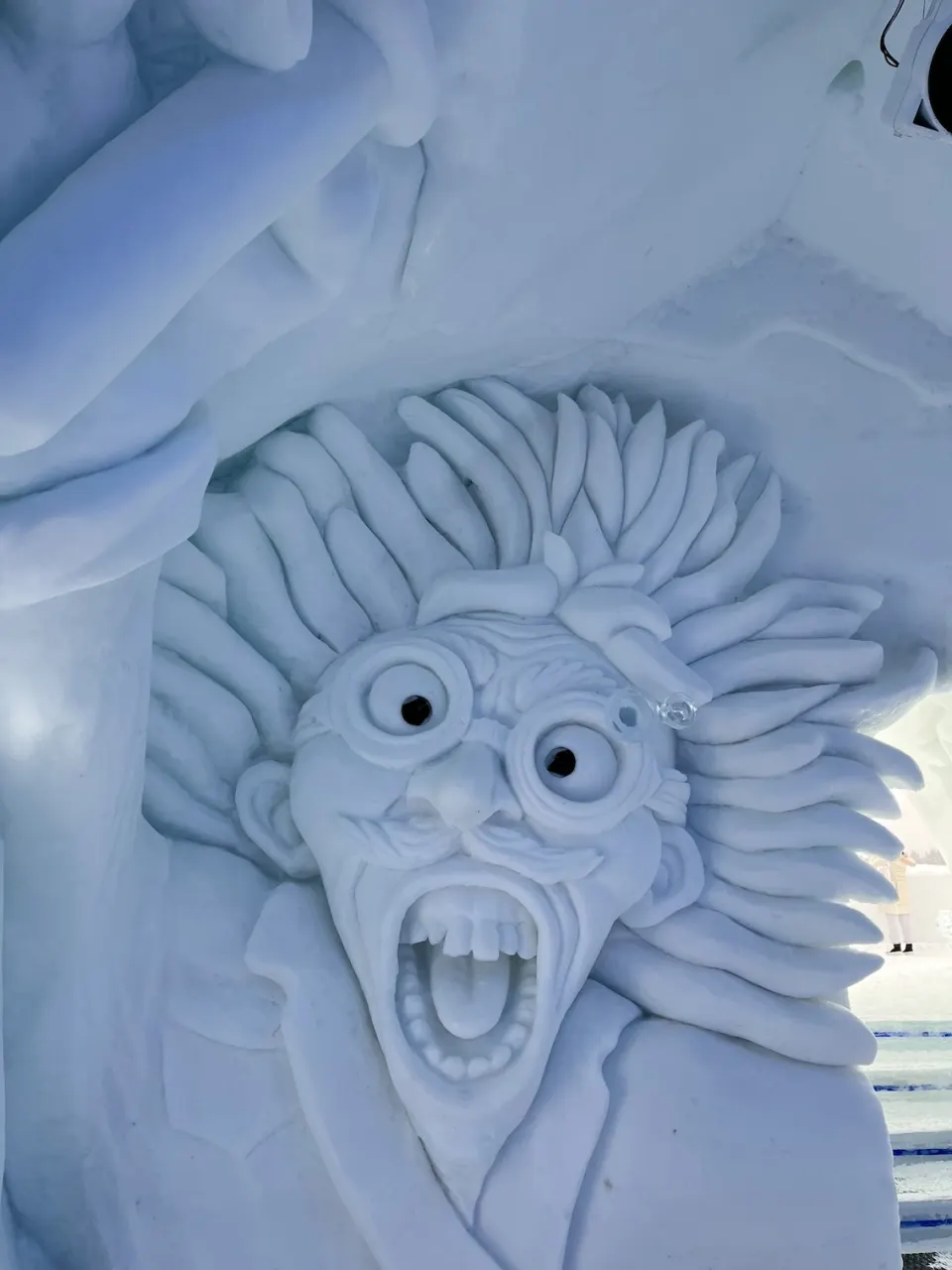 Expressive face carved into a blue-white ice sculpture